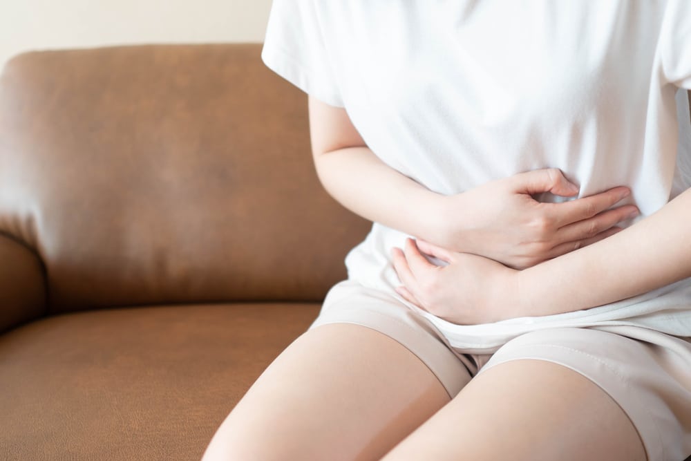 Young,Female,Suffering,Form,Stomach,Ache,While,Sitting,On,Couch